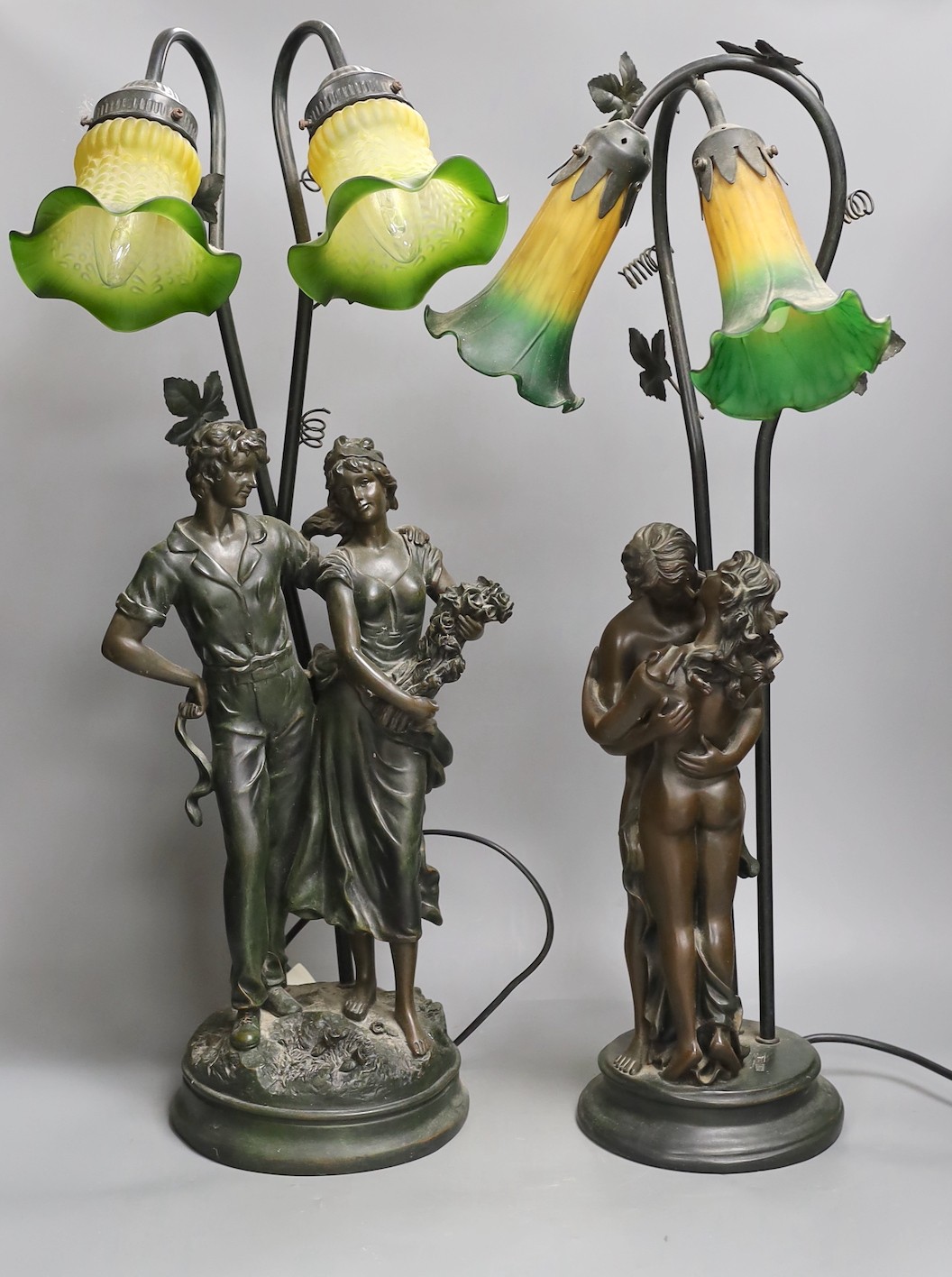 Two bronzed metal figural table lamps, with Art Nouveau style glass shades, 66cm total